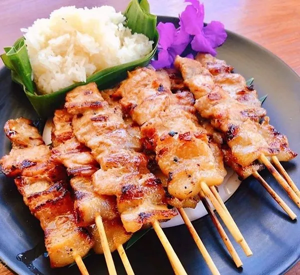 "Thai BBQ with the Best BBQ Tool Set - A mouthwatering Thai BBQ spread on a grill with a variety of grilled meats, veggies, and seafood."